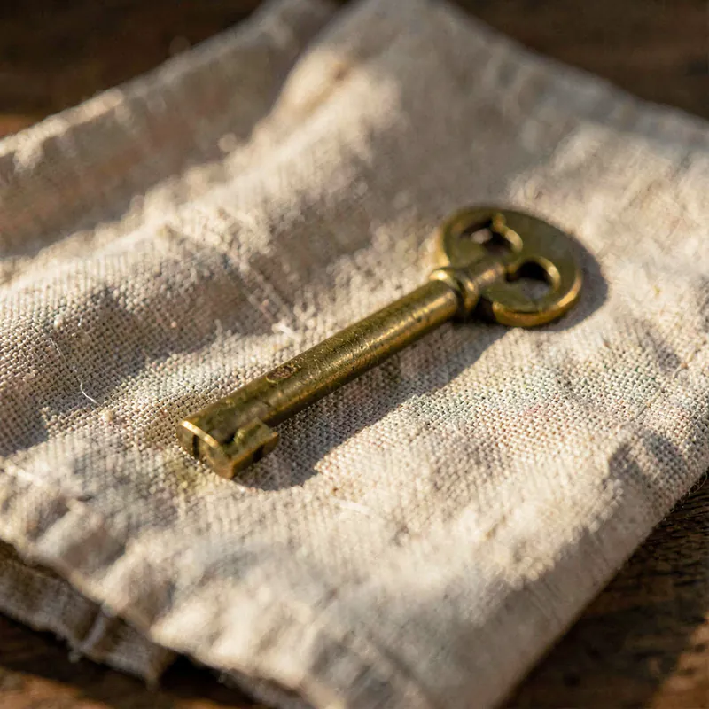 A single brass door key resting on folded natural linen