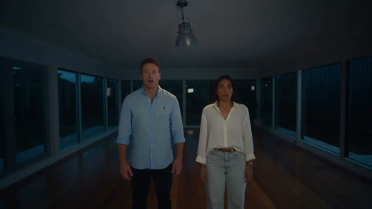 A couple standing in an empty living room at dusk, looking up at the room around them