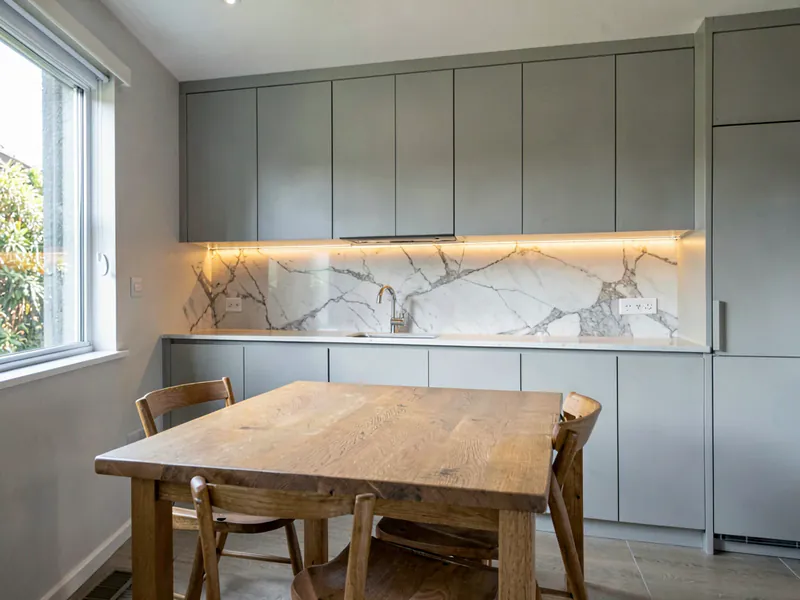 An empty pale grey Australian kitchen with a solid oak table and two empty chairs